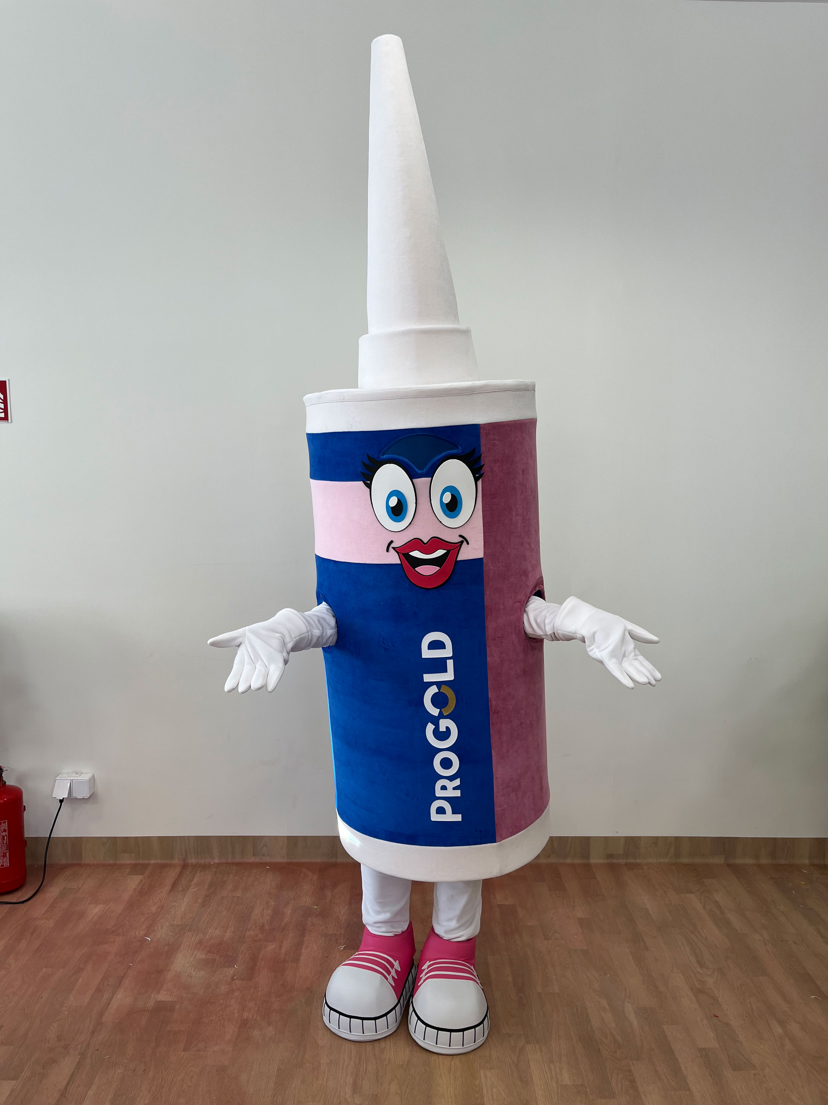 Na fotografii widnieje strój reklamowy stylizowany na butelkę pozujący do zdjęcia w siedzibie firmy Elabika